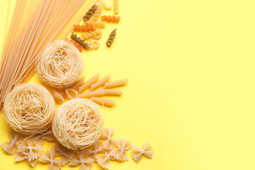 Composition with different types of raw pasta on yellow background
