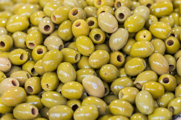 Green pitted olives closeup, background of green olives, street food market. Selective focus