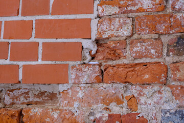 A fragment of an old red brick wall. Wall restoration site with new bricks