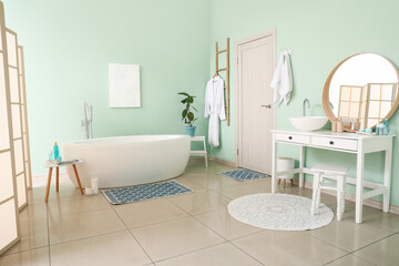 Interior of bathroom with modern bathtub and ceramic sink near mirror