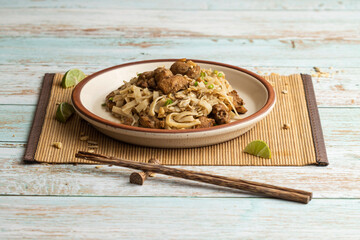 Pad thai plato con tallarín y pollo en mesa de madera azul