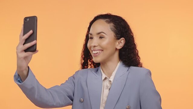 Business woman, selfie and smile in studio for social media profile picture and motivation. Happy model person with phone on an orange background for content creator post or testimonial video online