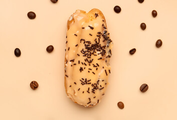 Delicious eclair and coffee beans on beige background