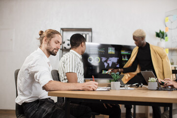 Confident caucasian man working using laptop with financial report at office. Male partners using huge modern display and digital gadgets. Overwork and deadlines concept.