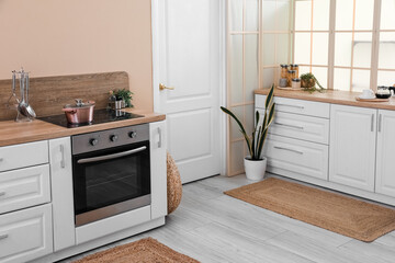 Interior of modern kitchen with white counters and electric oven