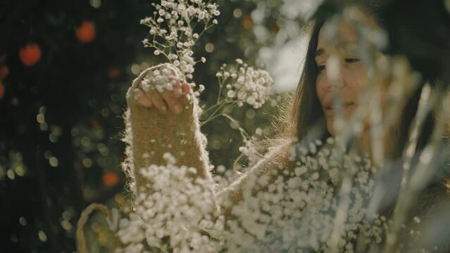 Slow motion shot of a beautiful woman holding white flowers in the orange garden