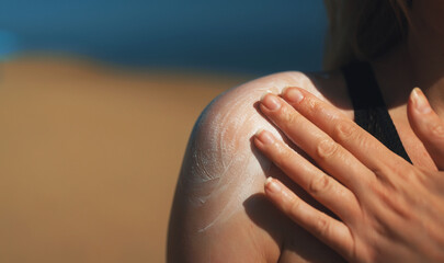 Woman applying sunblock cream on her shoulder.