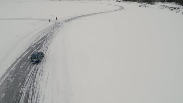 Winter fun filmed from a helicopter. Clip. Winter drift in cars that go to competitions and people watching around.