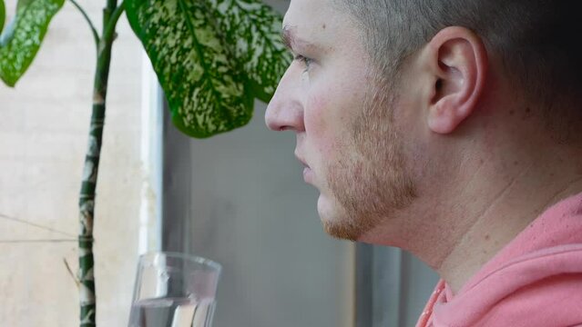 A man drinks medical pills with water, a young man takes the medicine on schedule, a man's hand holds a medical pill in his hand with a glass of water. The concept of treatment with pharmaceutical dru