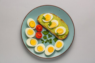 Plate with delicious avocado toast, boiled eggs, tomatoes and parsley on grey background
