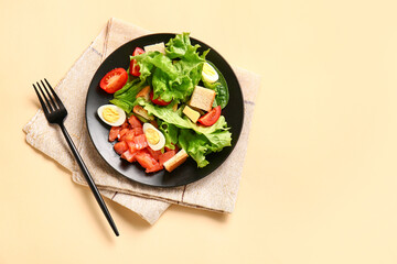 Plate of delicious salad with boiled eggs and salmon on beige background
