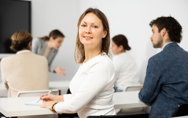 Focused adult female student sitting in college class - obrazy, fototapety, plakaty