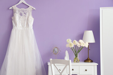 Interior of dressing room with flowers in vase, table and wedding dress