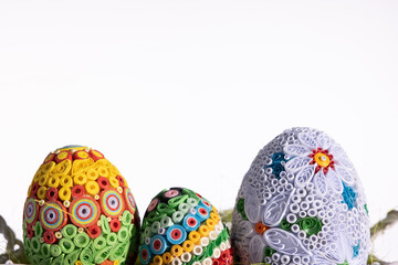 In the foreground are Easter eggs made by hand from paper and in the background is a pure white background.