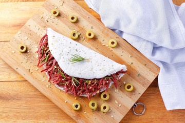 Tapioca or beiju stuffed with dried meat, jerked beef on a rustic wooden table. Typical Brazilian food