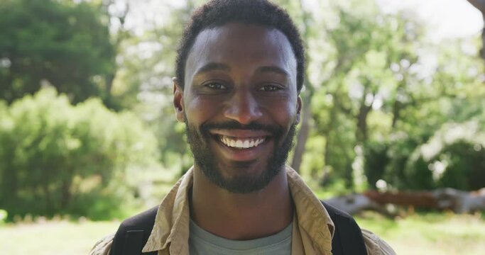 Portrait of happy african american man looking at camera in park, slow motion