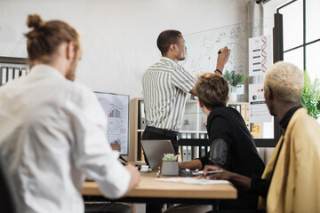 Multiracial male business people having briefing about financial situation at company. African man pointing on glass board with various graphs and charts. Cooperation and brainstorming concept.