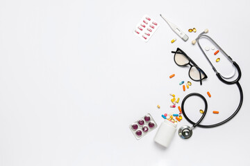 Pills with eyeglasses, stethoscope and thermometer on white background. World Health Day