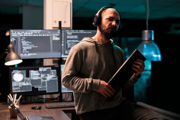 Cheerful developer fooling around with keyboard playing guitar, working on user interface with...