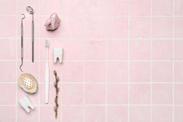 Dental tools with plastic teeth, Easter egg, rabbit and willow branch on pink tile background