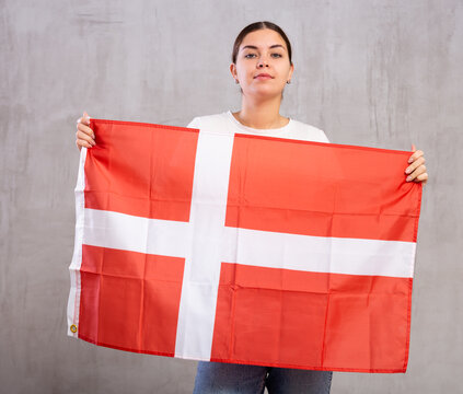 Young serious woman holding national flag of Denmark in her hands