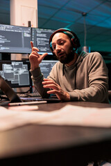 System engineer talking on online videoconference with laptop and webcam, using remote videocall to...