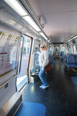 Blonde adult woman in an empty Washington subway train wearing blue jeans while using public transport