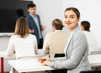 Obraz premium Portrait of smiling young woman smiling at camera during studying of foreign language with group of students in class