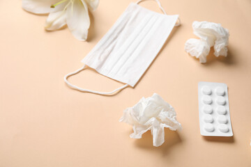 Medical mask with pills, flower and crumpled tissues on beige background. Seasonal allergy concept