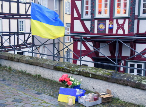 Blumen, eine Kerze und die ukrainische Fahne zum ersten Jahrestag des Überfalls der Ukraine durch Russland