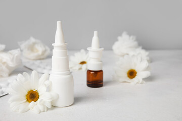 Obraz na płótnie Canvas Nasal drops with pills, flowers and tissues on table near grey wall. Seasonal allergy concept