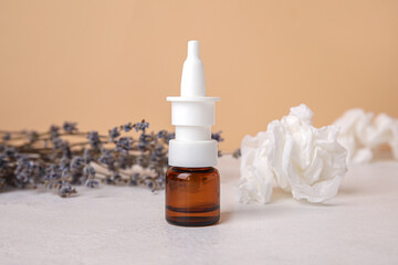 Nasal drops with flowers and tissues on table near beige wall, closeup. Seasonal allergy concept