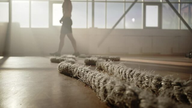 Battle ropes lying on floor in gym on background of athlete relaxing after intense cardio workout