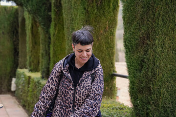 Fototapeta na wymiar portrait of lgbt non binary person in leopard coat looking down in a botanical garden.Gay Pride's day