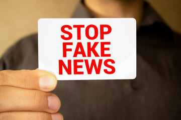 Woman holding megaphone and placard with text STOP FAKE NEWS on dark background