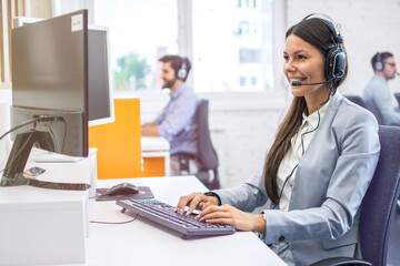 Smiling woman operator agent with headset responding to client's messages during online chat at customer support department. Online support, call center, helpdesk concept. - obrazy, fototapety, plakaty