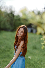Woman smile with teeth in the spring on a sunny day happily walking in nature against the green grass, the concept of women's body health