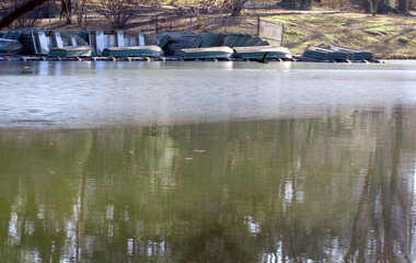 rowboats waiting for spring near the lake in central park in the off season with thawing ice 