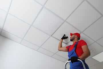 Electrician repairing ceiling light indoors, low angle view. Space for text