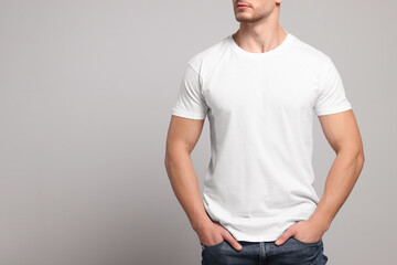 Man wearing white t-shirt on light grey background, closeup. Mockup for design - obrazy, fototapety, plakaty