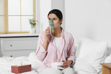 Sick young woman using nebulizer on bed at home - obrazy, fototapety, plakaty