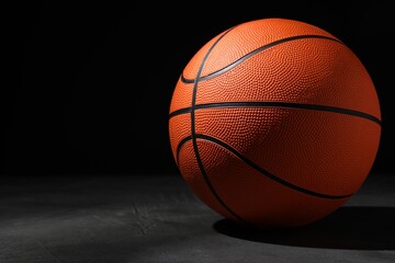 Fototapeta Basketball ball on grey stone table against dark background, space for text obraz
