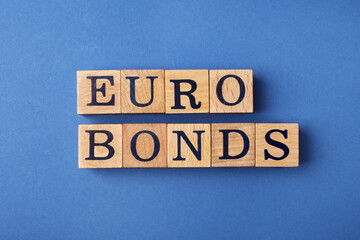 Fototapeta premium Word Eurobonds made of wooden cubes with letters on blue background, flat lay