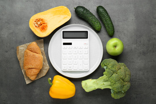 Calculator and food products on dark grey table, flat lay. Weight loss concept