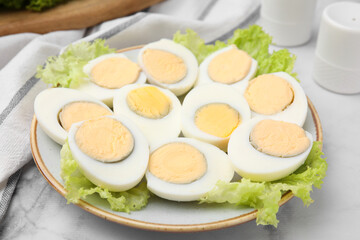 Fresh hard boiled eggs and lettuce on white marble table