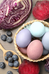 Colorful Easter eggs painted with natural dyes and ingredients on wooden table, above view