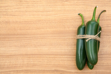 Fresh ripe green jalapeno peppers on wooden table, top view. Space for text