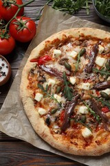 Tasty pizza with anchovies and ingredients on wooden table, flat lay