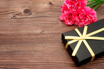 Fototapeta premium Mother's Day carnations and gifts (wood grain background)