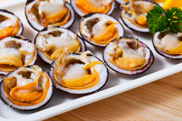 Raw bivalve mollusks (European bittersweet) served with lemon on plate